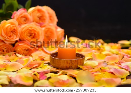 Lying down rose with orange rose petals with candle in bowl â??black background