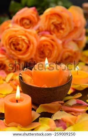 Lying down rose with many rose petals with candle in bowl