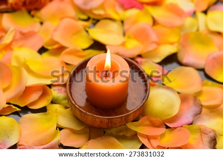 Many rose petals with candle in bowl