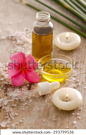 wooden background -frangipani, oil and pile of salt,green plant ,candle