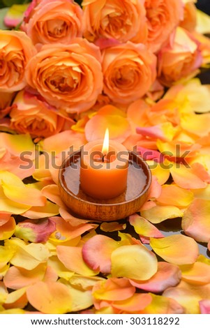 Rose with many rose petals with candle in wooden bowl