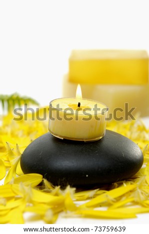 Yellow candle on stone and handmade Soap on yellow flower peals