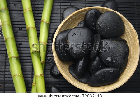 Wooden bowl of zen stones and bamboo grove on bamboo stick straw mat