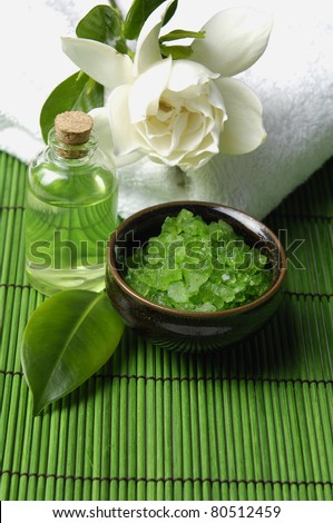 bath salt and gardenia flower on towel with essential oil on green mat