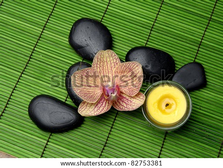Beautiful orchid and pile zen stones and candle on mat