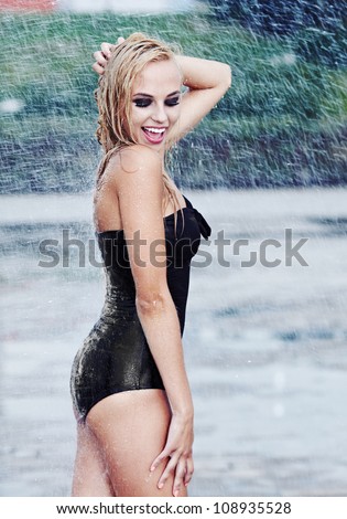 Young sexy girl walking along wet street in rain