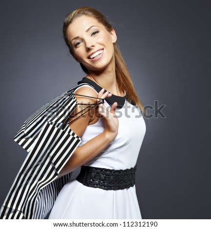 Shopping woman holding bags, isolated on gray studio background.
