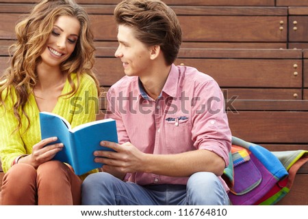 Beautiful couple reading book outdoors