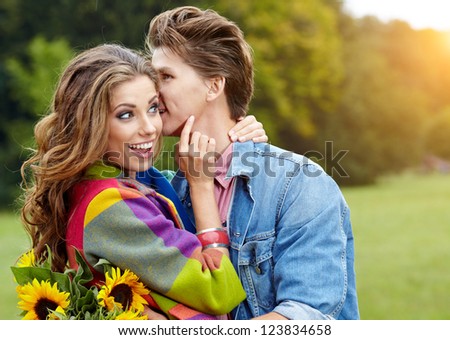 Loving young man hugging his girlfriend with sunflowers in their hands