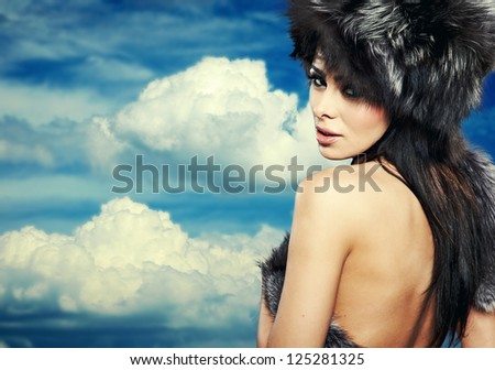 Fur Fashion. Beautiful Girl in Fur Hat. Winter Woman Portrait on sky