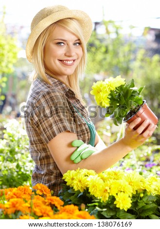Garden center worker smiling and holding up yellow flower