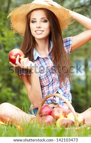 Apple woman. Very beautiful ethnic model eating red apple in the park.