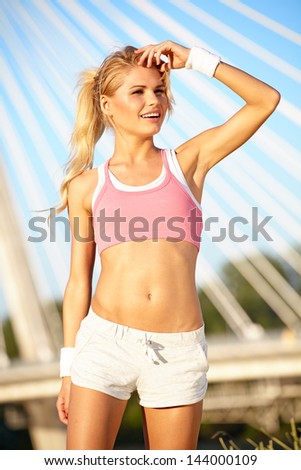 Sporty fitness woman outdoor workout. Young runner woman smiling happy resting after jogging training