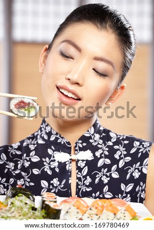 Beautiful young woman eating sushi. Shallow depth of field, focus is on the eyes.