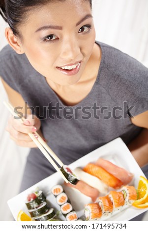 Beautiful young woman eating sushi. Shallow depth of field, focus is on the eyes.