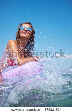 very happy woman on pink air bed in sea