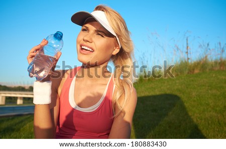 fitness and lifestyle concept - woman drinking water after doing sports outdoors