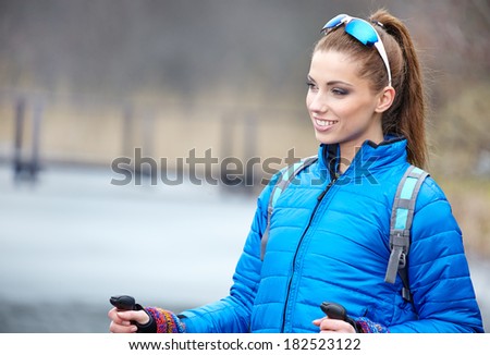 Closeup of young woman with Nordic walking poles in spring village