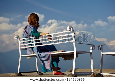woman sitting on a bench on a background of mountains