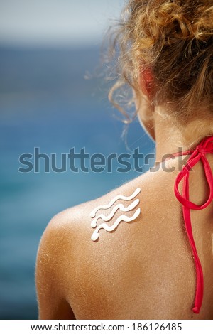 Woman with suntan lotion at the beach in form of a waves