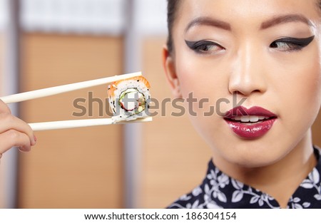 beautiful asian woman eating sushi with chopsticks