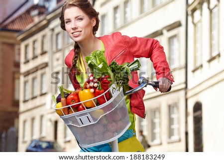 Pretty spring  woman with bicycle and groceries in old town street.
