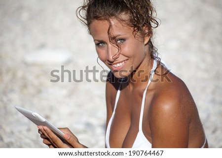 Happy woman reading a tablet reader on the beach
