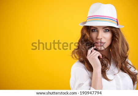 young happy girl in hat on yellow background