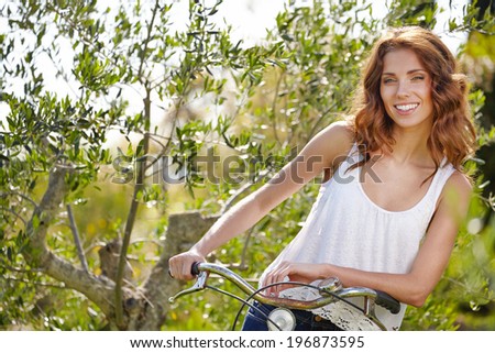 Pretty young woman rwith old bike in a country road.
