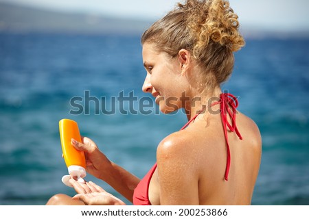 Woman applying sunscreen solar cream.