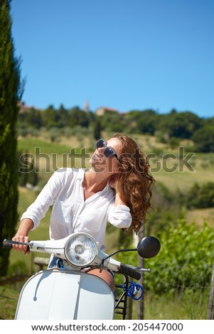 Young beautiful italian woman sitting on a italian scooter in tuscany outdoor