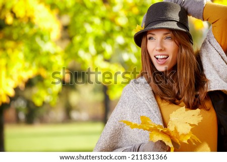 Young woman with autumn leaves in hand and fall yellow maple park  background
