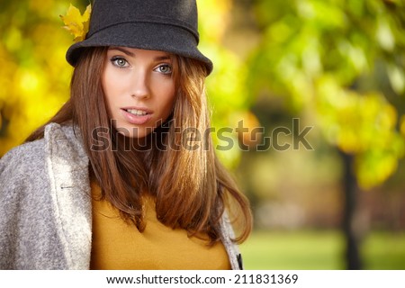 Young woman with autumn leaves in hand and fall yellow maple park  background
