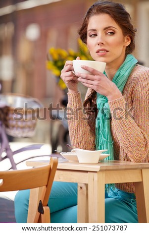 beautiful young girl drinking coffee in a old town cafe - outdoor portrait