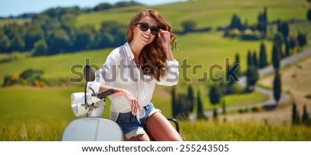 Young beautiful italian woman sitting on a italian scooter in tuscany outdoor
