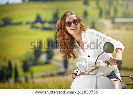 Young beautiful italian woman sitting on a italian scooter in Italy hills