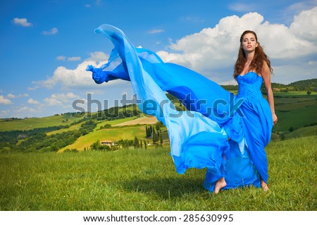 Happy woman in blue dress in green hills.