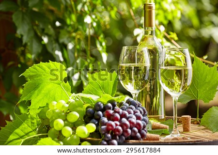 Grape and white wine on wooden barrel on garden terrace