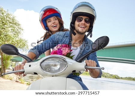 Cheerful couple riding vintage scooter