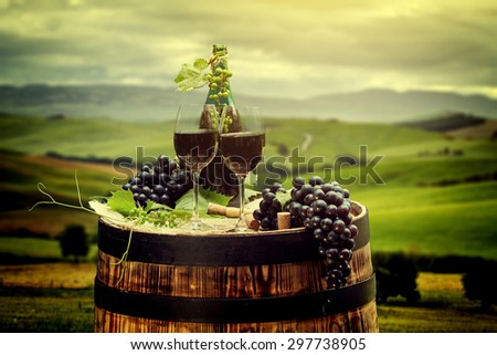 Red wine bottle and wine glass on old wood  barrel. Beautiful Tuscany background