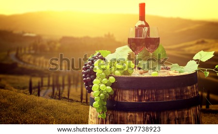 Red wine bottle and wine glass on old wood  barrel. Beautiful Tuscany background