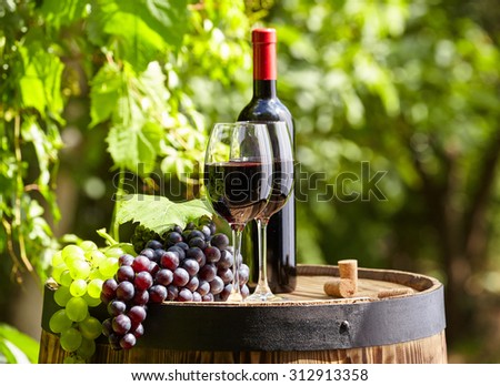 Red wine bottle and wine glass on old barrel.
