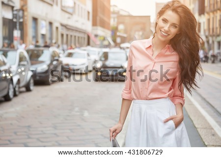 Close-up Fashion woman portrait of young pretty trendy girl posing at the city in Europe,summer street fashion,holding retro fedora hat popular until the 60s.laughing and smiling portrait.trendy