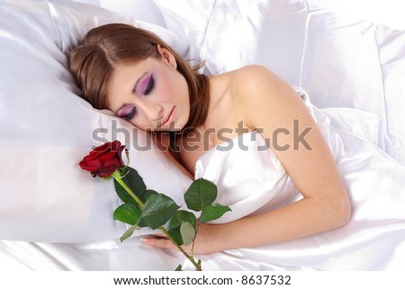 Portrait of young beautiful sleeping woman with rose on bed at bedroom
