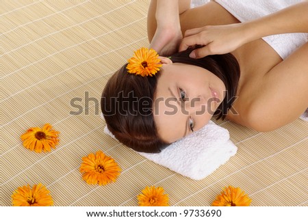 Portrait of sexy and Beautiful woman laying on bamboo mat around orange flowers