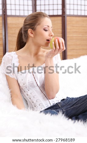 Young beautiful woman eating green apple