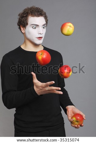 Portrait of Mime with red apple on grey background