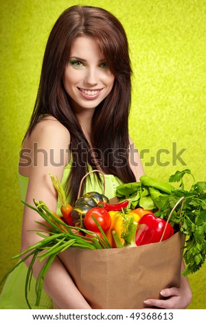 woman holding a grocery bag full of fresh and healthy food isolated on green background