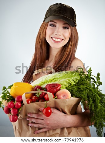 Portrait of happy woman holding a shopping bag full of groceries on white background