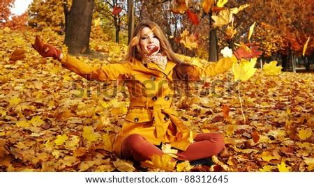 Portrait of an autumn woman lying over leaves and smiling